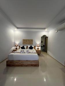 a bedroom with a large bed and two tables at Gamat Sunset Cottage and Resto in Nusa Penida