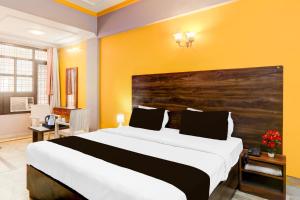 a bedroom with a large bed and a yellow wall at Super Hotel O Insaf Nagar Munshipuliya Formerly Vibrant in Lucknow