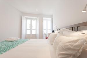 リスボンにあるFLH Alfama Bright Apartmentの白いベッドルーム(大型ベッド1台、白い枕付)
