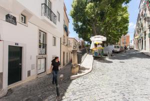 リスボンにあるFLH Alfama Bright Apartmentの石畳の通りを犬歩く女