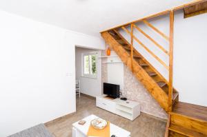 a living room with a staircase and a tv at Apartments LeviAna in Saplunara
