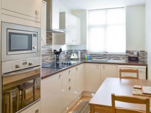 a kitchen with white cabinets and a table and a microwave at Anchor's Away in Filey
