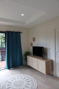 a living room with a flat screen tv on a cabinet at Aumihi Bungalow in HUH