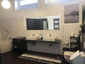 a bathroom with two sinks and a mirror and a toilet at EcoLodge Loft Comfortable holiday residence in Oesterdeichstrich +20 photos