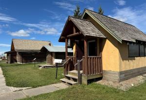 eine kleine Hütte mit Veranda und Treppe im Gras in der Unterkunft Coast Fort St John Hotel in Fort Saint John