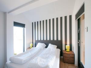 a bedroom with a white bed and a striped wall at Villa Oesterdam Sleeps 8 persons in Tholen