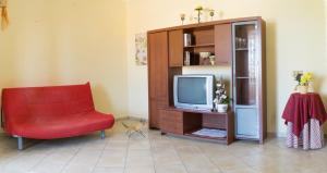 een woonkamer met een rode stoel en een tv bij Casa Vacanza da Luisa in San Giovanni Suèrgiu