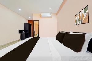 a bedroom with a white bed with black and white pillows at Collection O Surathkal Beach Formerly Coastal Lodge in Suratakal +40 photos