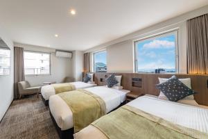 a hotel room with three beds and a window at HOTEL MYSTAYS Hakodate Station in Hakodate