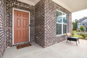 a brick house with a red door and a chair at New Charming Surburban Retreat 12 mins to Lakepoint in Acworth