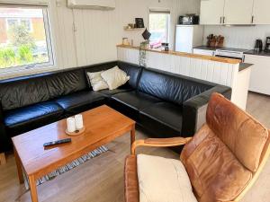 a living room with a black leather couch and a table at 6 person holiday home in Hals-By Traum in Hals +24 photos
