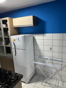 a white refrigerator in a kitchen with a blue wall at Apartamento completo Corumbá in Corumbá