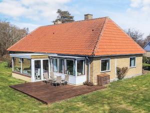 Una casa con techo naranja, terraza y sillas. en 8 person holiday home in Harpelunde, en Harpelunde 19 fotos más