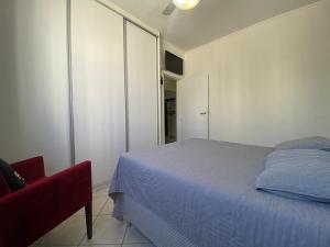 a bedroom with a bed and a red chair at Apartamento próx praia in Balneário Camboriú