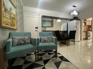 a living room with two chairs and a dining room at Apartamento próx praia in Balneário Camboriú
