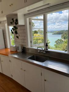 a kitchen with a sink and a large window at Raglan Beach Bungalow in Raglan +7 photos