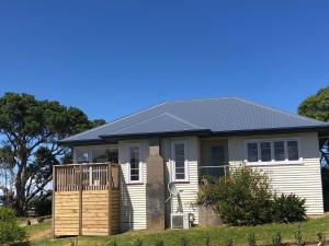 a small white house with a black roof at Raglan Beach Bungalow in Raglan
