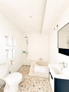 a white bathroom with a toilet and a sink at GreenCaldera - 1BR Guesthouse with Pool in Kintamani in Kubupenlokan