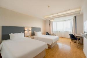 a hotel room with two beds and a desk at Hanting Hotel Beijing Railway Station Subway Station in Beijing