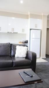 a living room with a black leather couch and a table at Renmark Holiday Apartments in Renmark +6 photos
