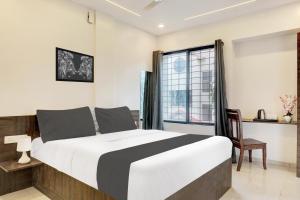 a bedroom with a bed and a desk and a window at Super Hotel O Laxman Nagar Baner in Pune