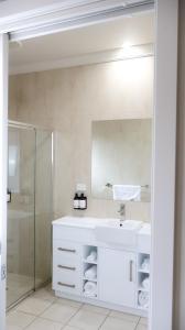 a white bathroom with a sink and a shower at Renmark Holiday Apartments in Renmark