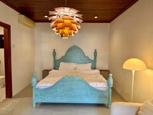 un letto blu in una camera da letto con lampadario a braccio di Chic Designer Master Bedroom in Shared Bungalow near LRT SS1 PJ a Petaling Jaya
