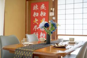 a dining room table with a vase of flowers on it at Private lodging MOKUBA  +10 photos
