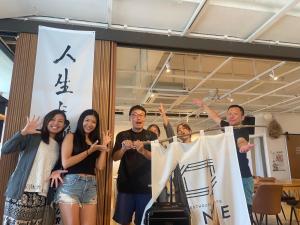 宮古島にあるONE Miyakojimaの旗の横に立っている人々のグループ