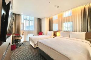 a hotel room with two beds and a flat screen tv at Ramada Encore by Wyndham Busan Station in Busan