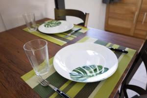 una mesa de madera con 2 placas blancas y una copa en Fare Miri Miri, en Haapiti