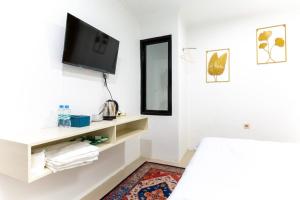 a white room with a tv on a wall at Escotel Journey Hotel Antapani in Bandung