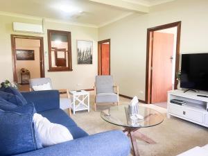 Una sala de estar con un sofá azul y un televisor. en Rhoda Avenue Residence, en Wagga Wagga