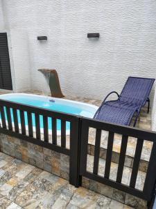 a deck with a hot tub and a chair at Casa do Sol III in Peruíbe