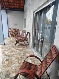eine Terrasse mit Stühlen und Tischen auf einer Veranda in der Unterkunft Casa do Sol III in Peruíbe
