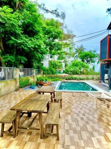 a patio with picnic tables and a swimming pool at Sea la vie - Do Son Beach Homestay in Ðố Sơn