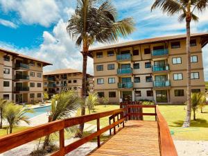 ein Holzsteg, der zu einem Resort mit Palmen führt in der Unterkunft Brisa Muro Alto - Flat na Praia in Ipojuca
