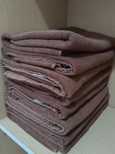 a stack of brown towels sitting on a shelf at Tracy Homestay Tmn Indah Jaya in Sandakan +16 photos