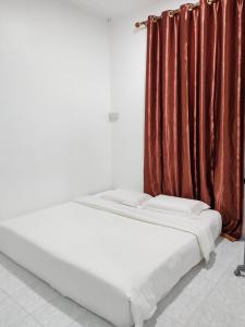 a bed in a room with a red curtain at Tracy Homestay Tmn Indah Jaya in Sandakan