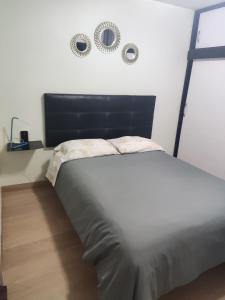 a bed in a bedroom with two mirrors on the wall at Habitación en apartamento compartido frente a Maiquetía! in Maiquetía