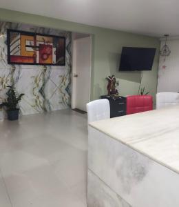 a living room with white chairs and a tv at Habitación en apartamento compartido frente a Maiquetía! in Maiquetía