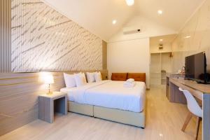 a bedroom with a white bed and a kitchen at i2 Resort Lampang in Sathani Nakhon Lampang