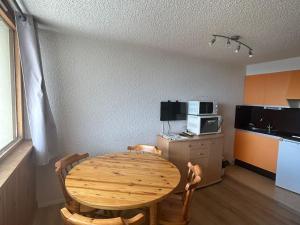 a room with a wooden table and a kitchen at Studio à Super Besse avec vue sur pistes et balcon - FR-1-814-16 in Besse-et-Saint-Anastaise +4 photos