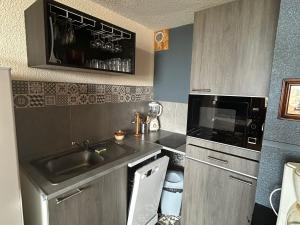 eine kleine Küche mit Spüle und Mikrowelle in der Unterkunft Studio charmant au centre de la station montagne, idéal pour 2 à 4 personnes - FR-1-814-4 in Besse-et-Saint-Anastaise