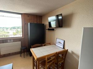 Kleines Zimmer mit einem Tisch und einem TV an der Wand in der Unterkunft Studio charmant au centre de la station montagne, idéal pour 2 à 4 personnes - FR-1-814-4 in Besse-et-Saint-Anastaise