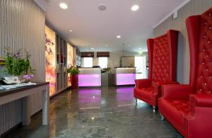 a lobby with red chairs and a kitchen with pink lights at Leonardo Hotel Nürnberg in Nürnberg +26 photos