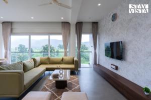 Una sala de estar con un sofá y un televisor. en StayVista at Amara Palms, en Igatpuri