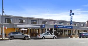 two cars parked in front of a building on a street at Comfort Inn Commodore Albury in Albury
