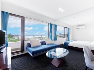 a hotel room with a bed and a couch and a tv at Pals Inn Katsuura in Katsuura
