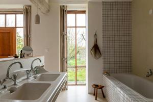 Neuvy-en-DunoisにあるCharming House In The Heart Of Beauceの洗面台2つと浴槽1つを備えたバスルーム